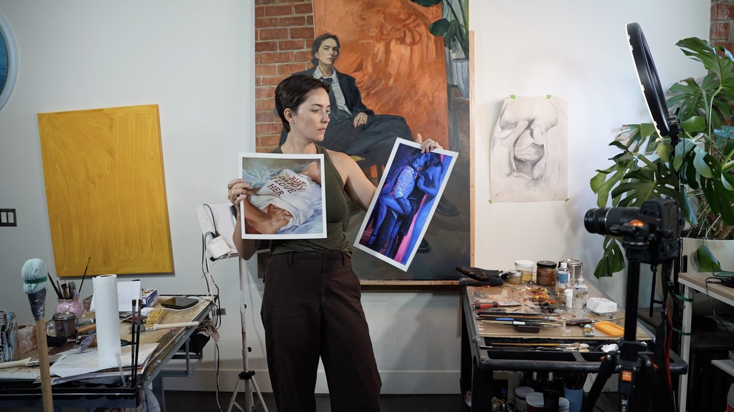 Halie Torris holding two of her prints in the studio